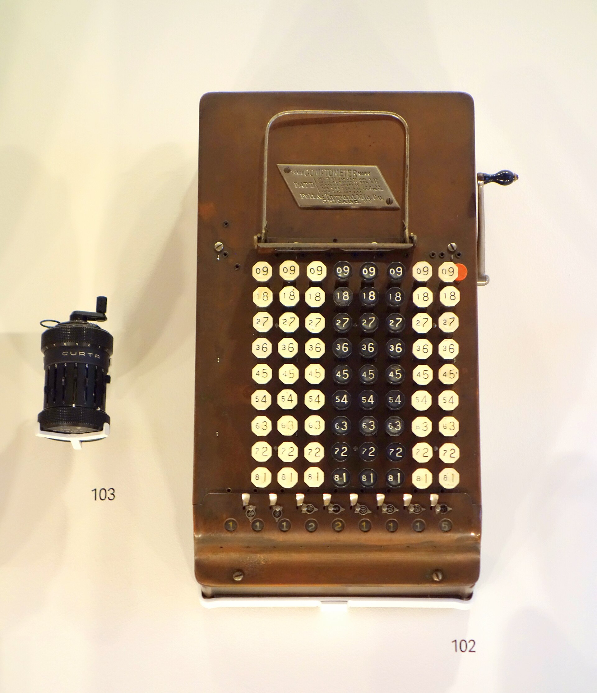 Figure 2 — Scale, stated bluntly: a 1915 Felt & Tarrant Comptometer beside a Curta, both in the Design Museum, London. Both machines do the same job.
