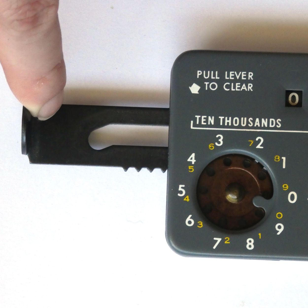 Figure 6 — The clearing lever of a grey Lightning pulled out to the left: a flat steel bar with a long slot and, along its lower edge, the teeth of the clearing rack. On the ten-thousands dial the stop tongue…