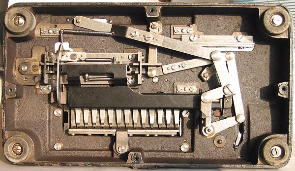Figure 6 — For comparison only: the open base of a Manus model D, the only published view of a Manus underside. The D's base is higher and its linkage is differently arranged, but the carriage spring, the div…