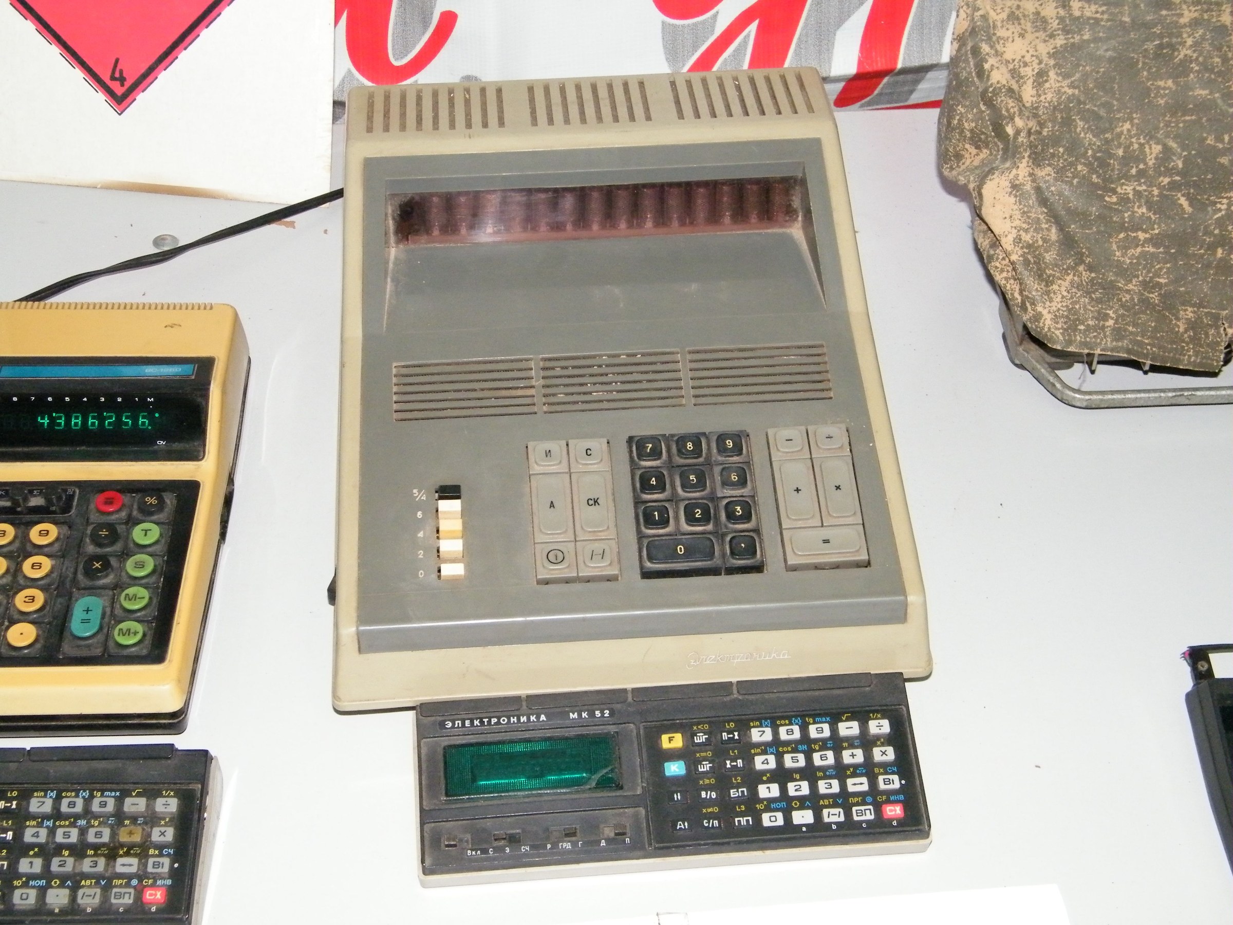 Figure 4 — A group of Soviet calculators in a museum display: desk machines with fluorescent and Nixie displays alongside the pocket models that followed them.