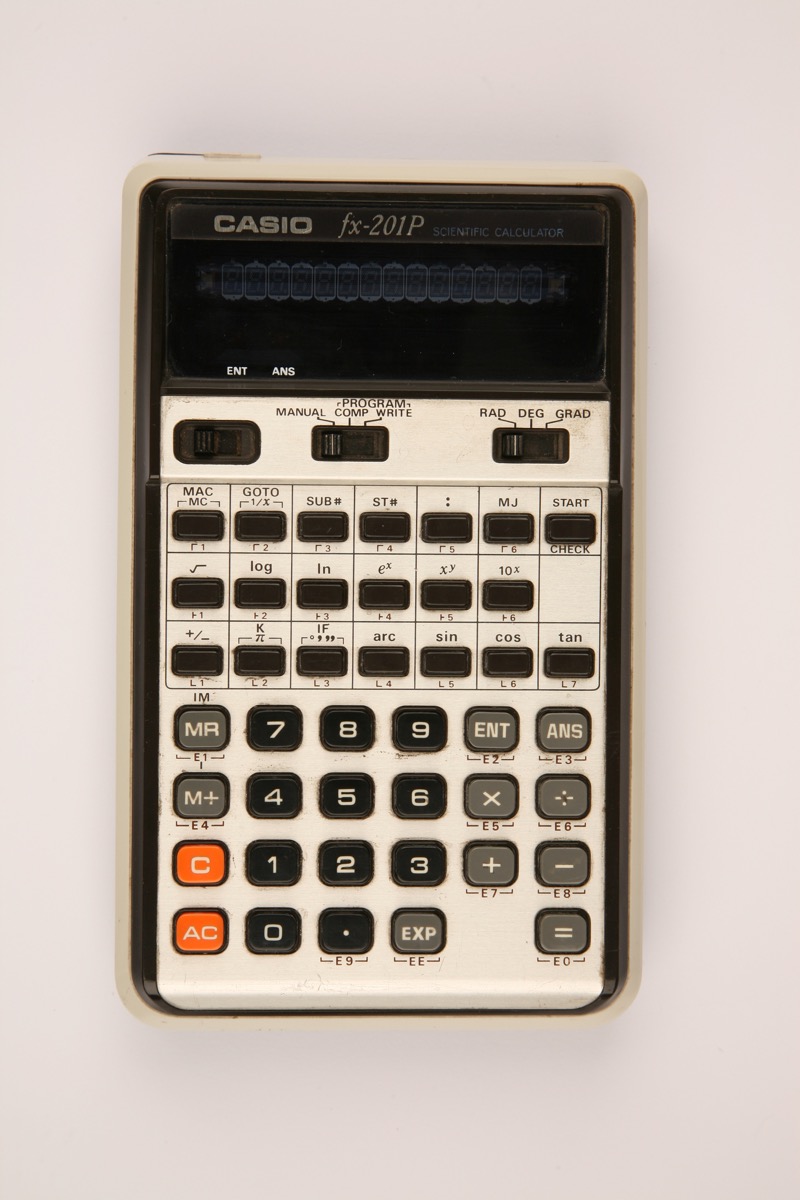 Figure 15 — The Casio fx-201P of 1976, a programmable pocket scientific with a green fluorescent display and a MANUAL/COMP/WRITE switch.