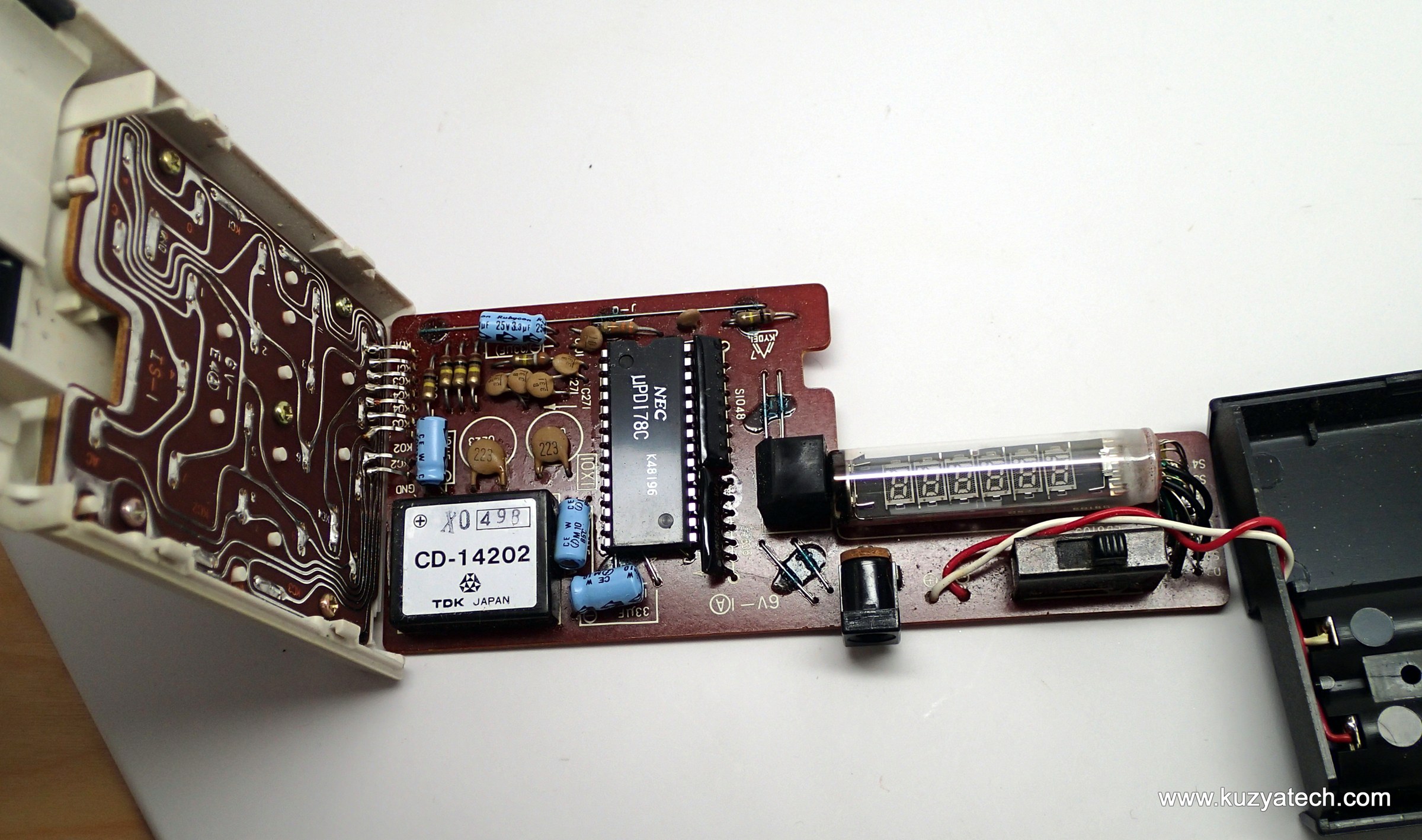 Figure 8 — Inside a Casio Personal-mini: the TDK CD-14202 converter module in the corner makes the tube's voltages from two AA cells; the NEC chip beside it is the whole calculator.